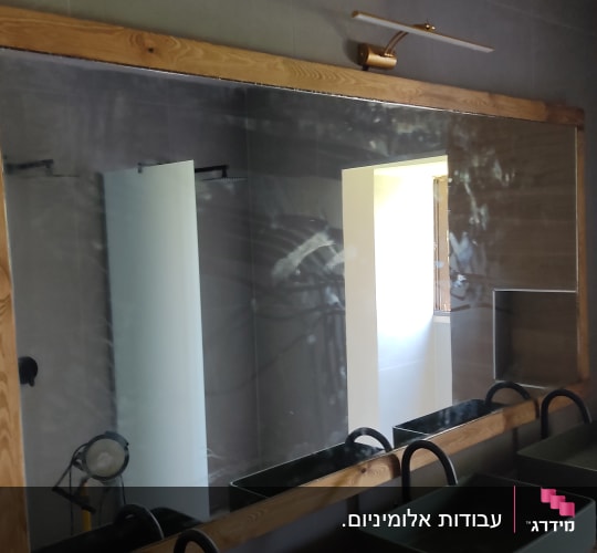 מראה גדולה עם מסגרת עץ ותאורה עליונה